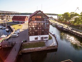 Un hotel con una estructura de entramado de madera llamativa, situado junto a un canal con barcos amarrados.
