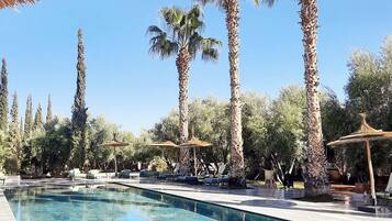 Una piscina al aire libre, camas de piscina gratis, sombrillas