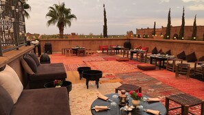 Une terrasse sur le toit, aménagée avec des coins salon, des tables et une rambarde décorative.