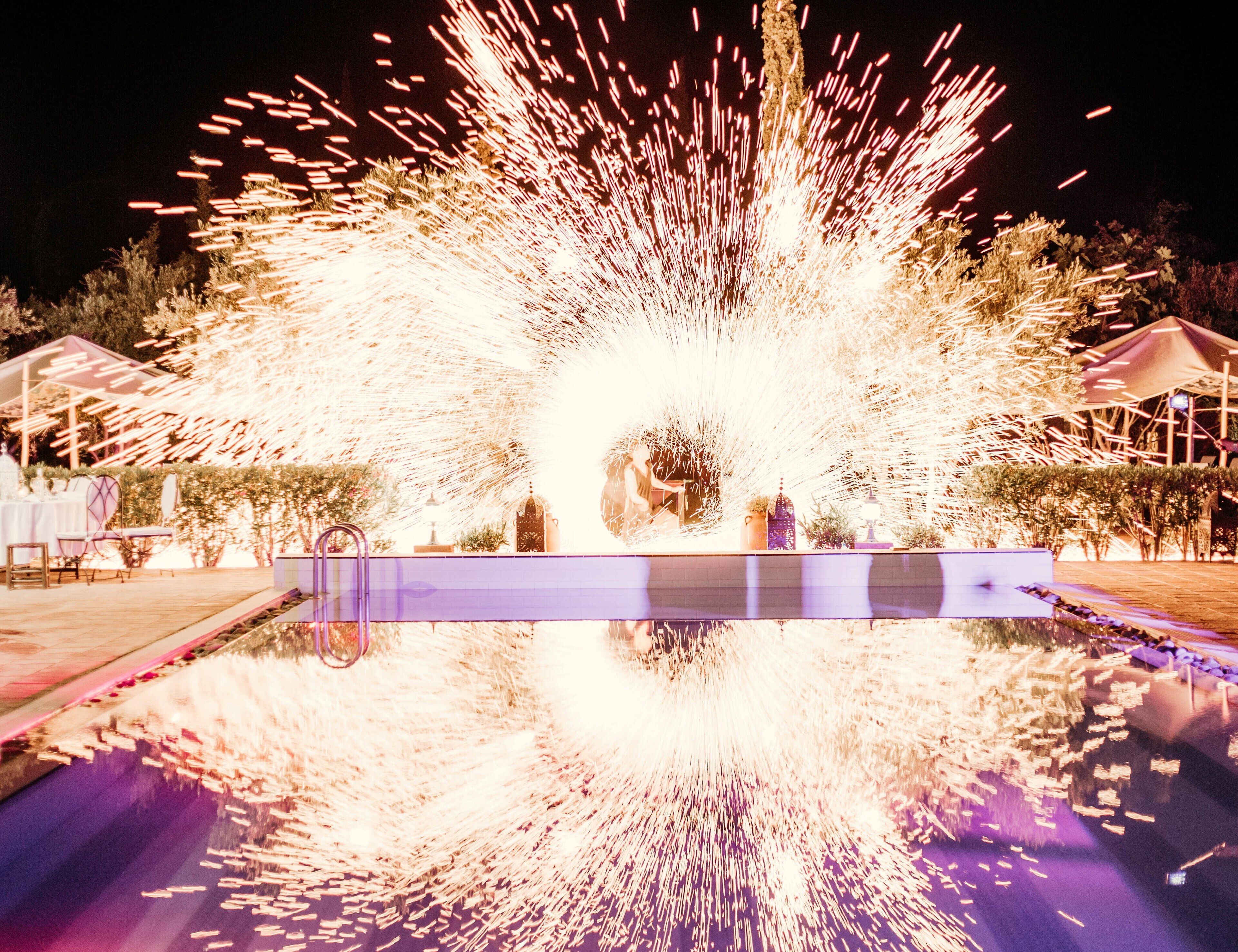 A fountain with water jets creating a circular spray pattern, surrounded by a reflective pool.