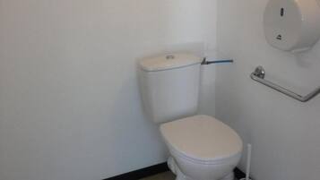 A small, clean bathroom with a toilet, a toilet paper holder, and a bidet.