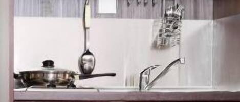 Une cuisine avec des armoires en bois, un évier en acier inoxydable et un égouttoir à vaisselle placé au-dessus du plan de travail.