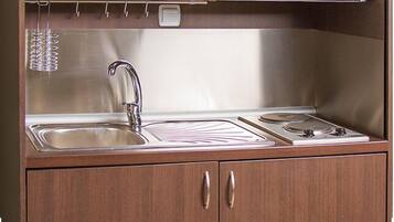Een kitchenette met een spoelbak, fornuis en opslagkastjes.