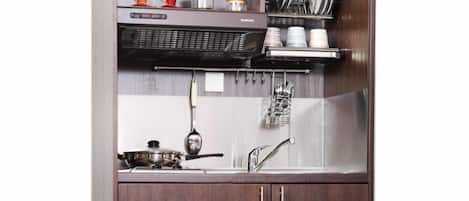 Una cocina con pileta, estufa y organizador de utensilios.