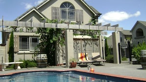 A house with a swimming pool, a covered patio, and a fenced garden area. - Lodge Bordeaux (Whangarei)