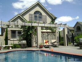 Una piscina al aire libre de temporada, sillones reclinables de piscina