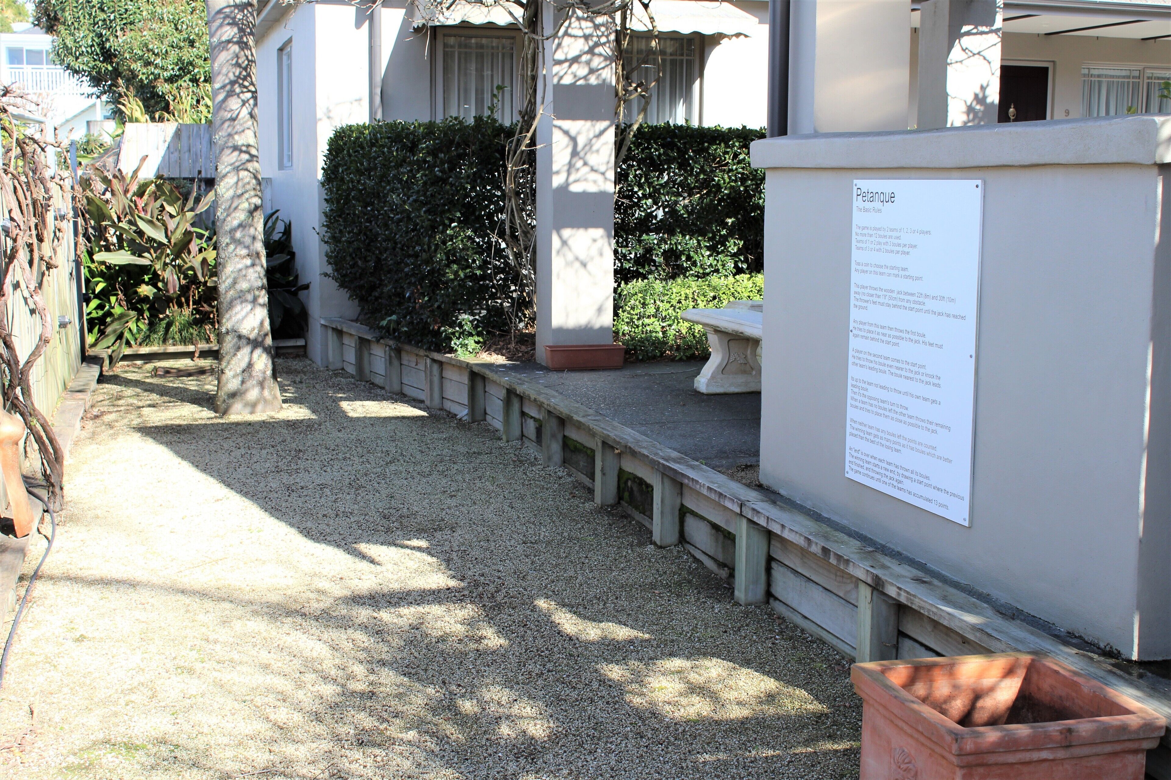 A gravel pathway leading to a building with a white exterior and a signboard.