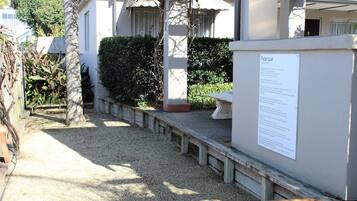A gravel pathway leading to a building with a white exterior and a signboard.