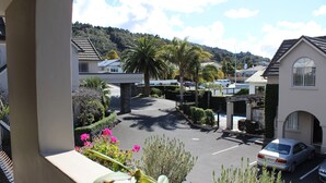 A residential street with parked cars, houses, and a hill in the background. - Lodge Bordeaux (Whangarei)