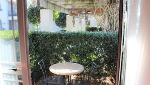 A glass door leading to an outdoor patio with a round table and two chairs. - Lodge Bordeaux (Whangarei)
