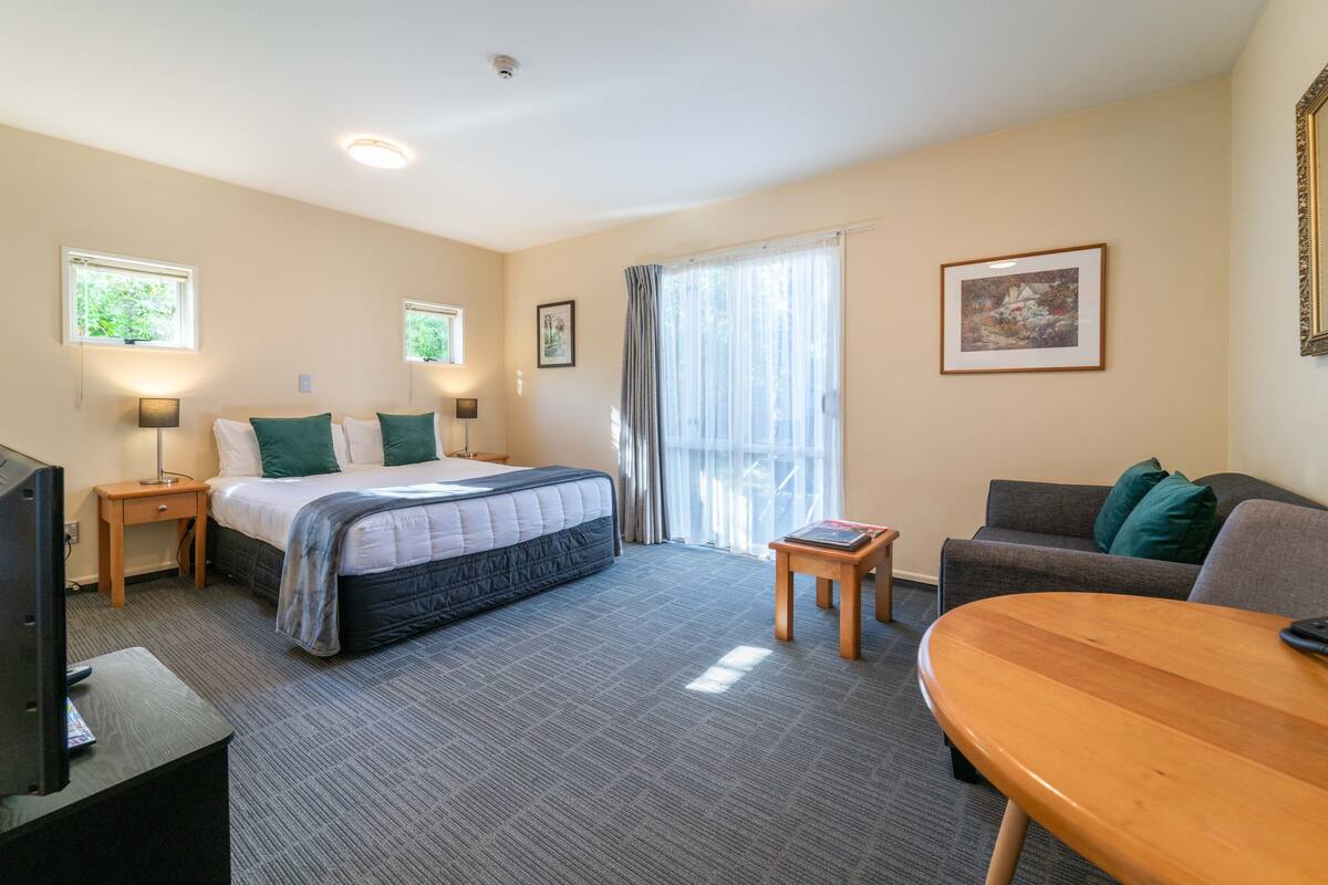 A hotel room with a bed, a TV, a desk, a chair, and a sofa.