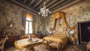 Un dormitorio lujoso con cama de dosel, muebles ornamentados y una araña.