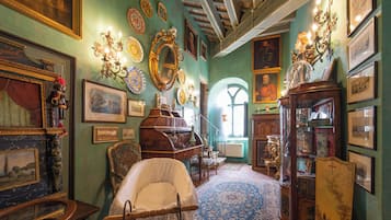 Quarto com móveis antigos, um espelho grande e várias molduras nas paredes.