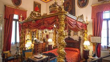 A luxurious bedroom with a four-poster bed, ornate ceiling, and classic furniture.