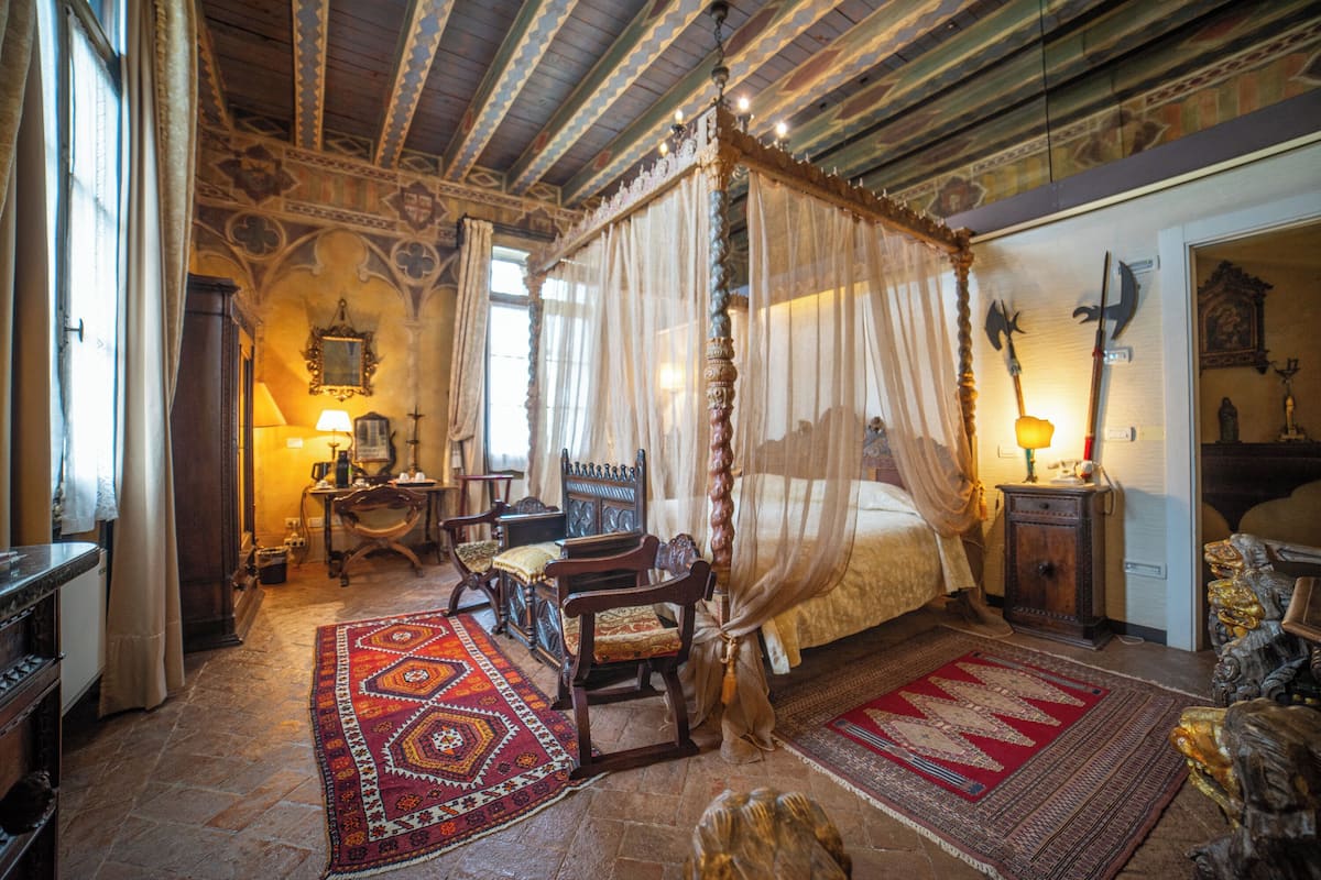 A traditional bedroom with a four-poster bed, ornate wooden furniture, and patterned rugs.
