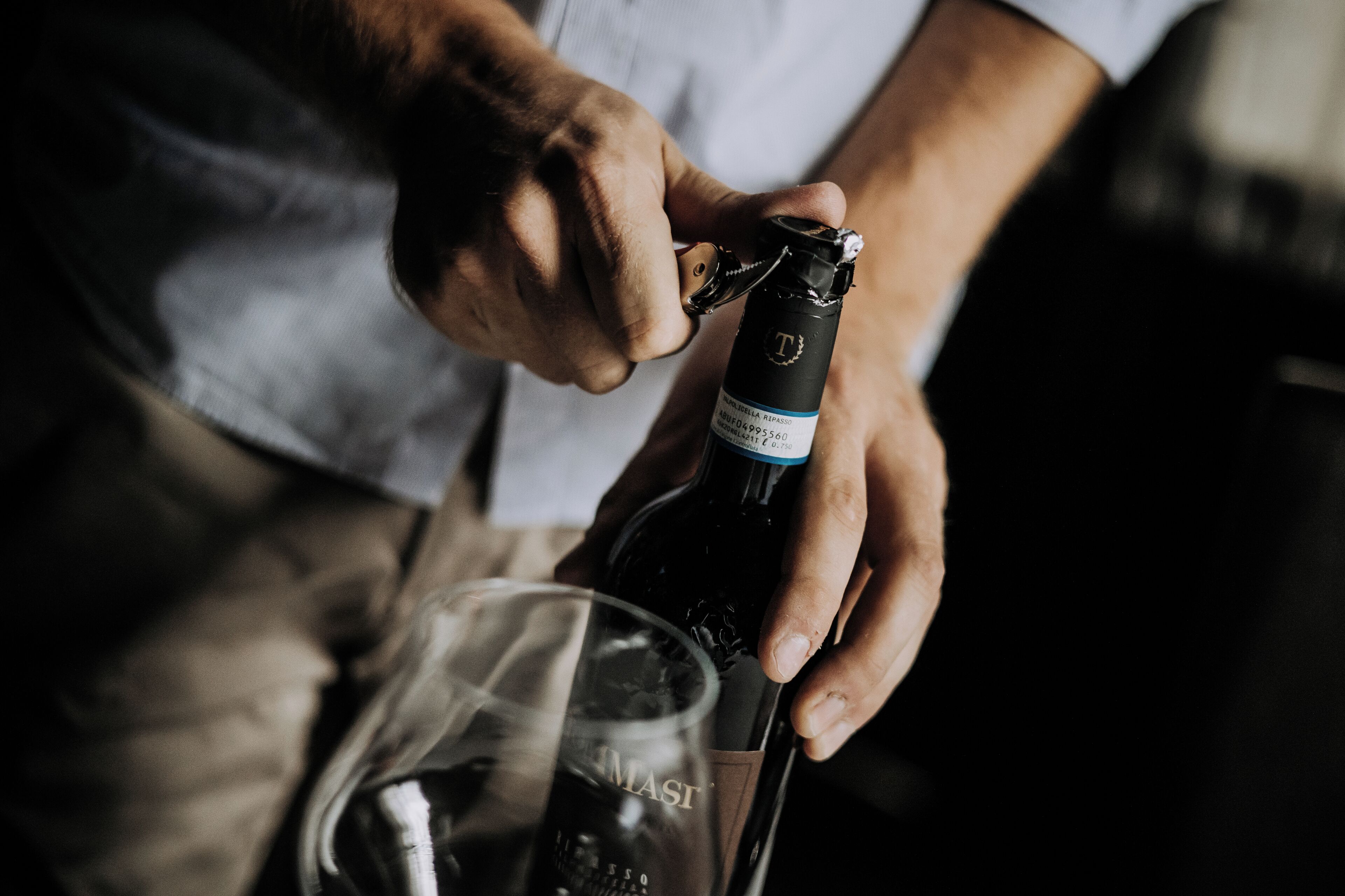 A person opening a bottle of wine.