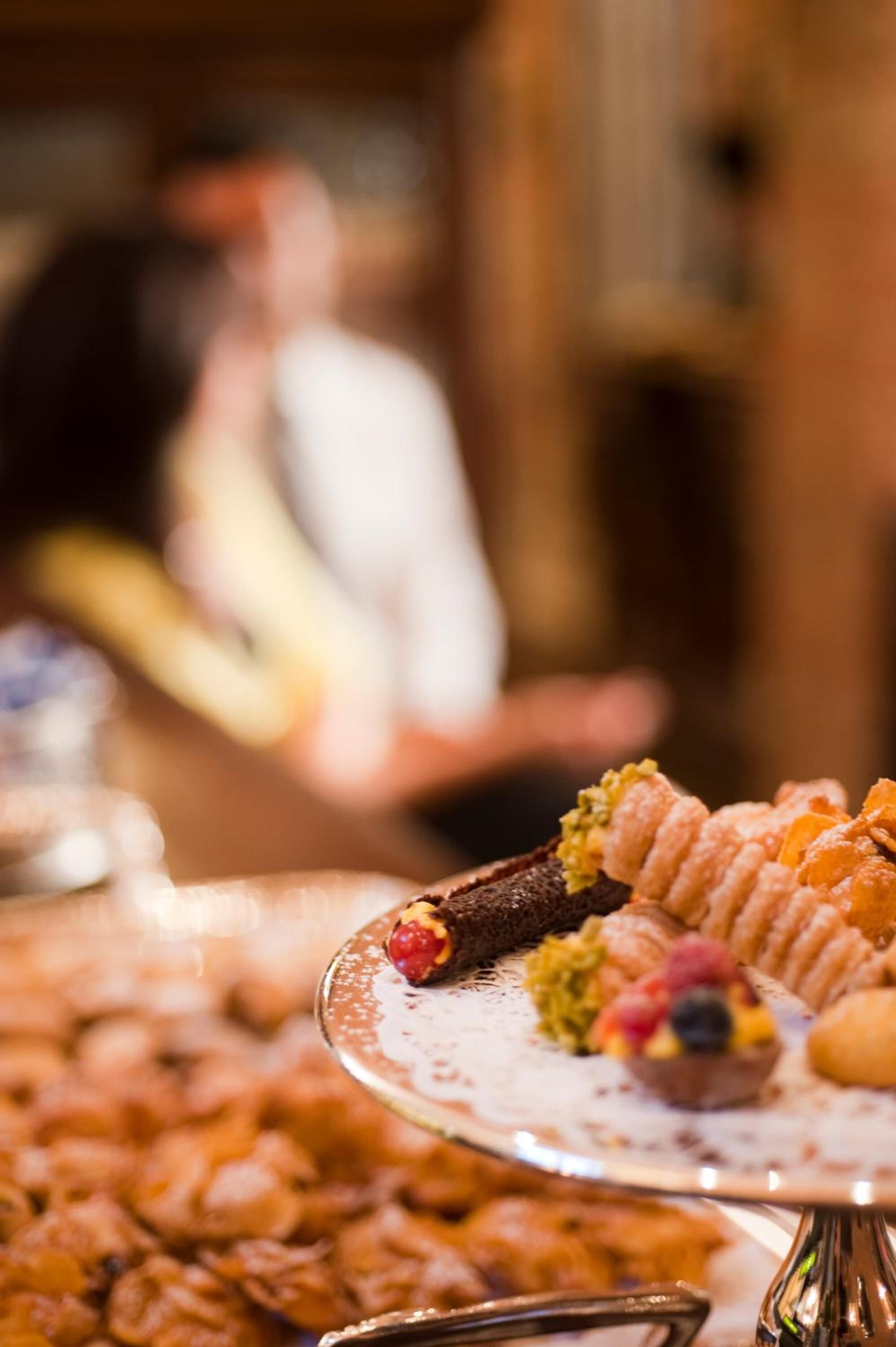 En buffetbod med forskellige desserter og en person i baggrunden.