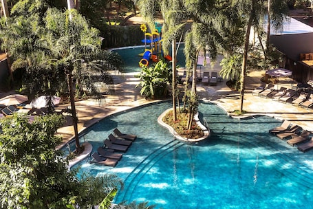 Una piscina al aire libre, sombrillas, sillones reclinables de piscina