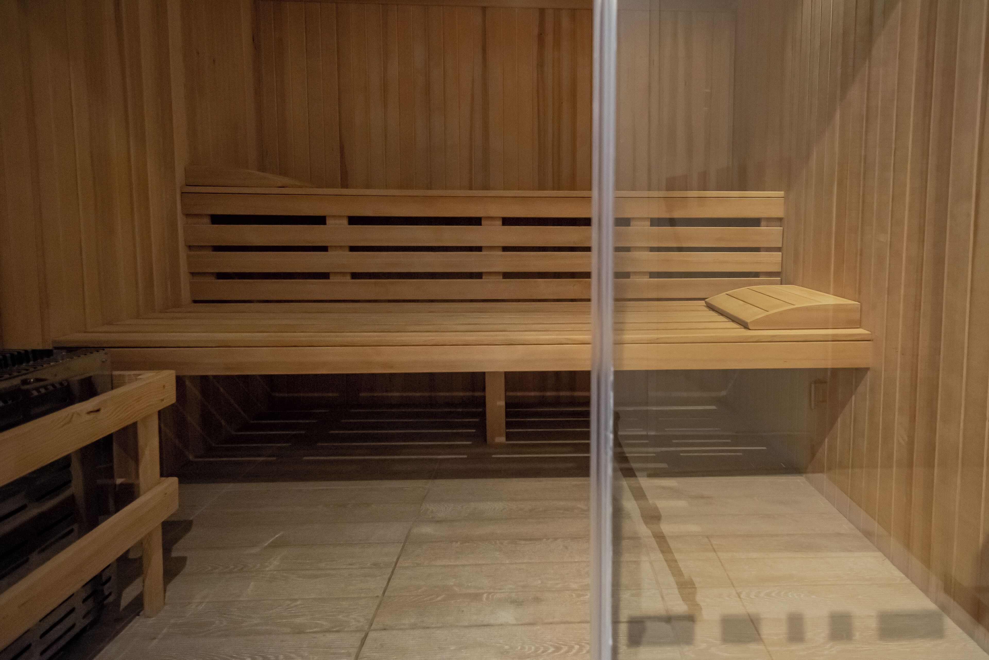 A sauna with wooden benches and a glass partition.
