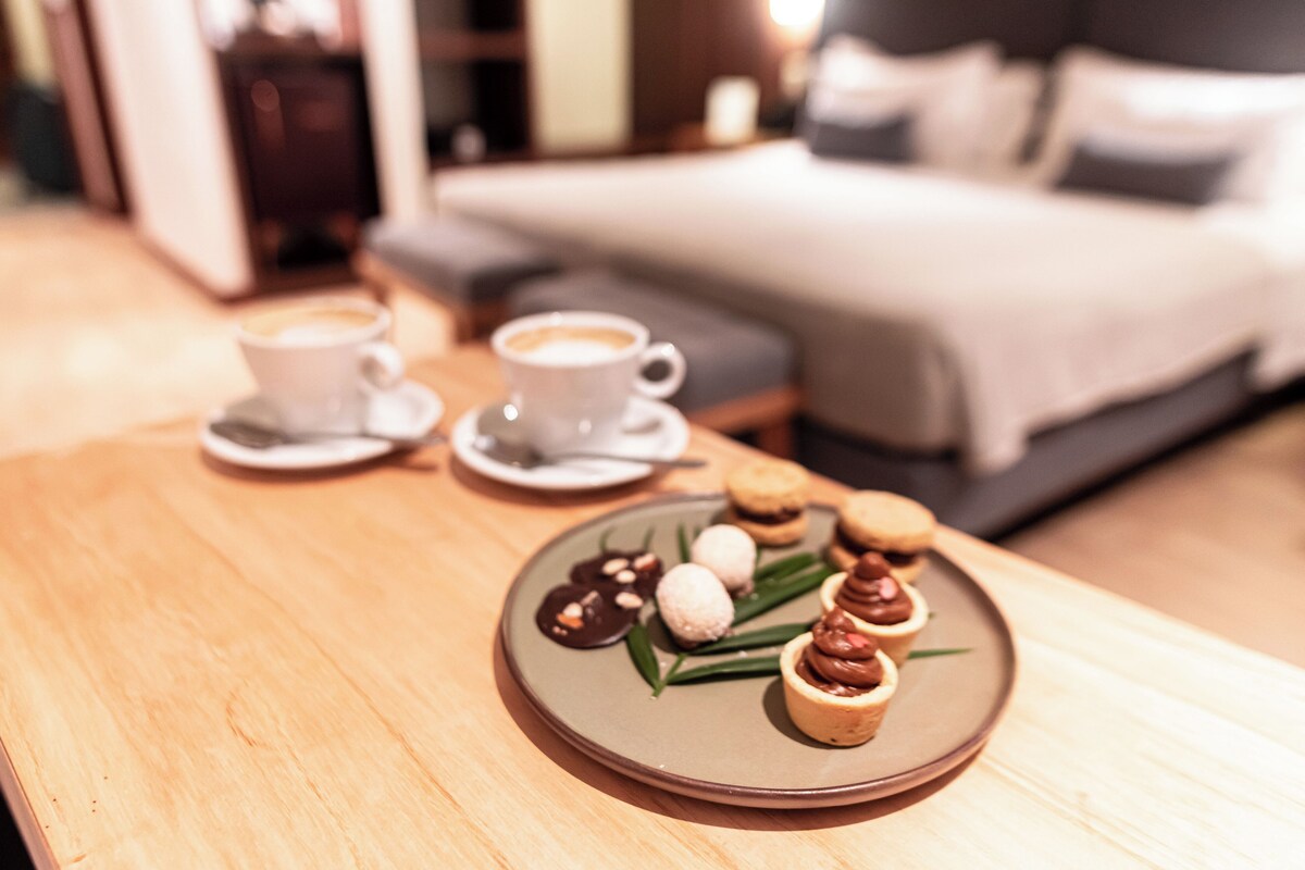 Een ontbijfwagen met gebak en een kop koffie op een houten tafel in een hotelkamer.