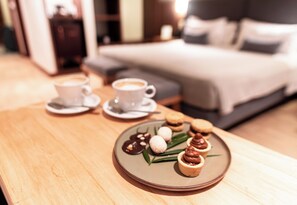 Bandeja de desayuno con pasteles y una taza de café sobre una mesa de madera en una habitación de hotel.