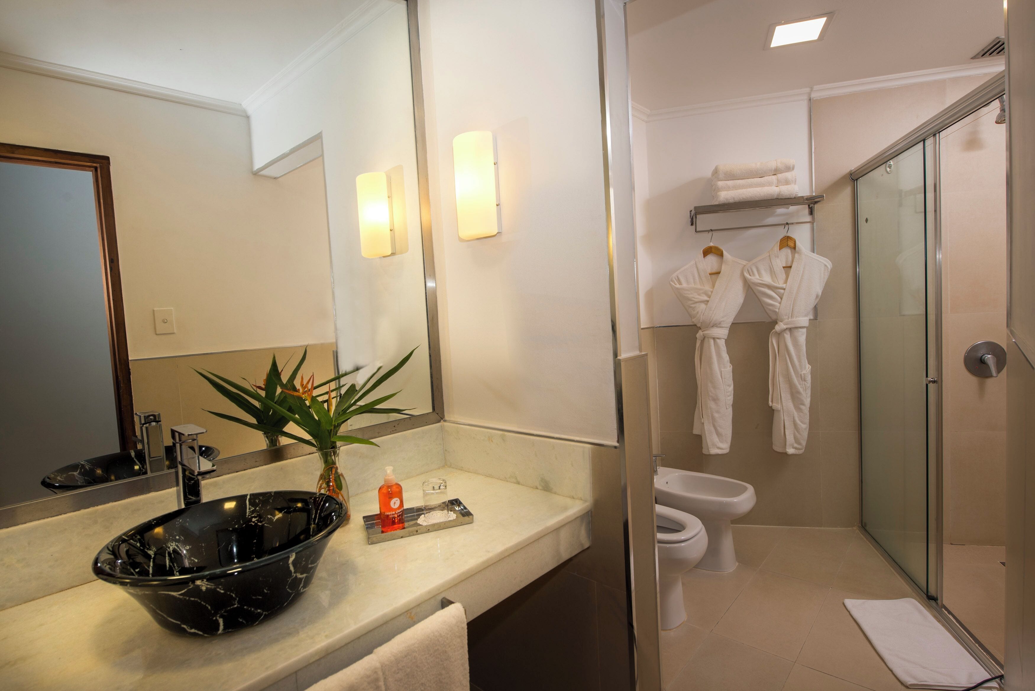 Une salle de bain moderne avec un lavabo en marbre noir, une douche en verre et des toilettes.