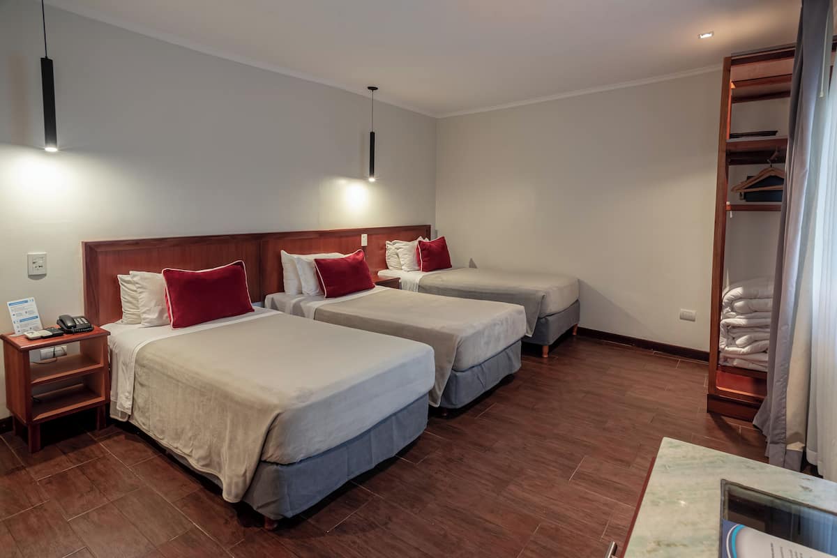 Ein Hotelzimmer mit zwei Einzelbetten, einem Holznachttisch mit Telefon und einem Kleiderschrank mit Kleidung.