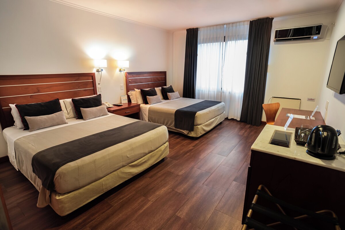 Een hotelkamer met twee bedden, een bureau, een stoel en een koffiezetapparaat.