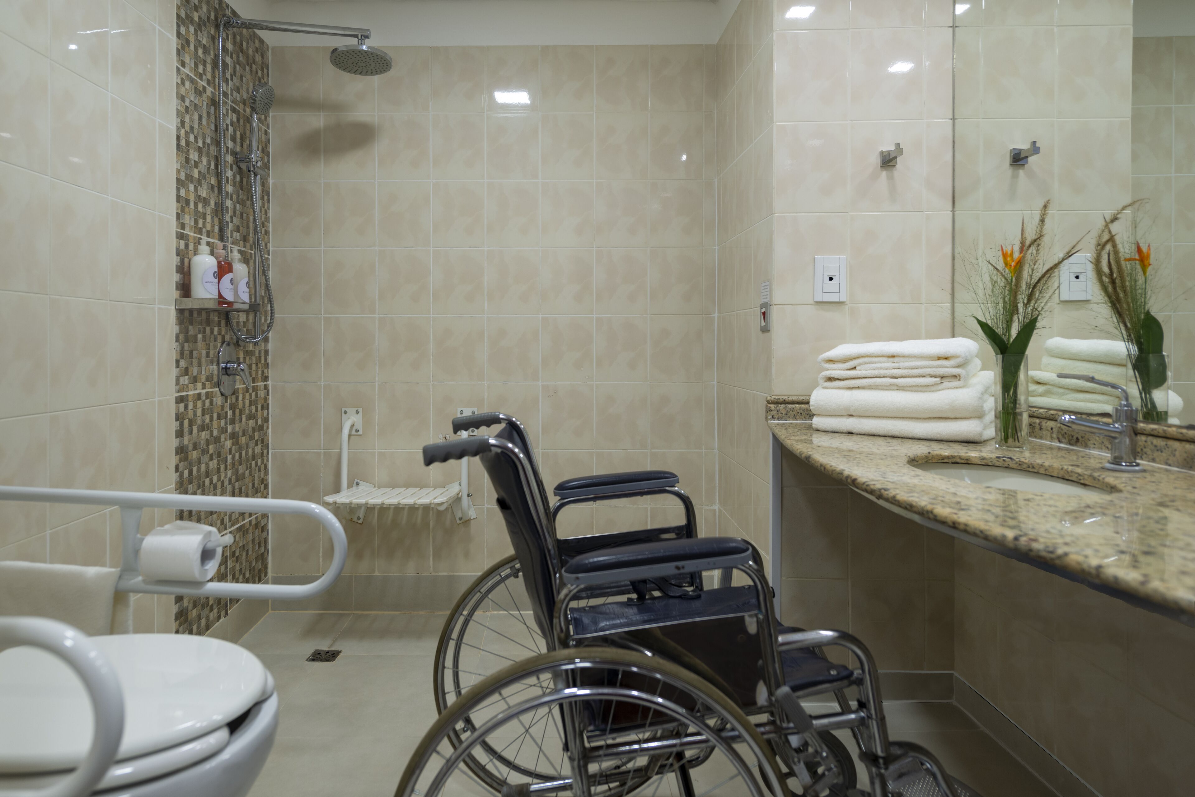 A bathroom with a shower, toilet, and two wheelchairs.