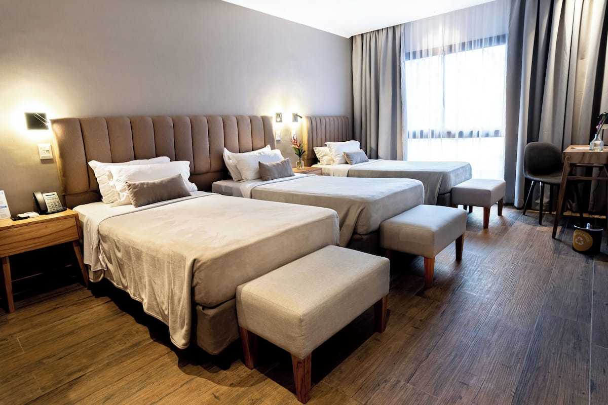 Ein Hotelzimmer mit zwei Betten, einem Schreibtisch, einem Stuhl und einem kleinen Tisch.