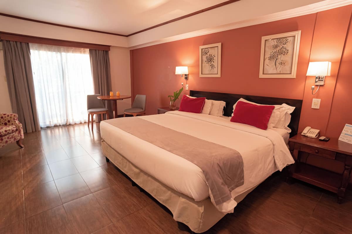 Ein Hotelzimmer mit einem großen Bett, einem Schreibtisch, einem Sessel und einem kleinen Tisch.