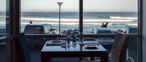 A table set for dining with a view of the ocean through large windows.