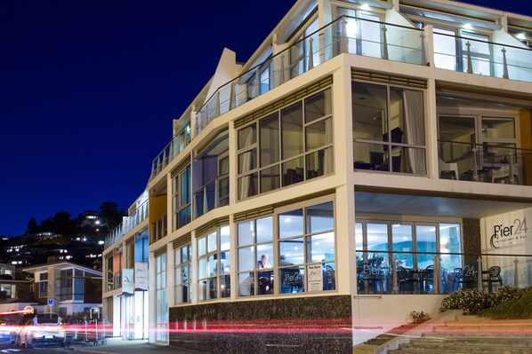 A modern building with large windows and a sign for Pier 24 restaurant & bar. - Hotel St Clair (Dunedin)