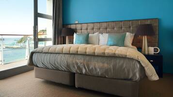 A bedroom with a large bed, a view of the ocean, and a balcony.