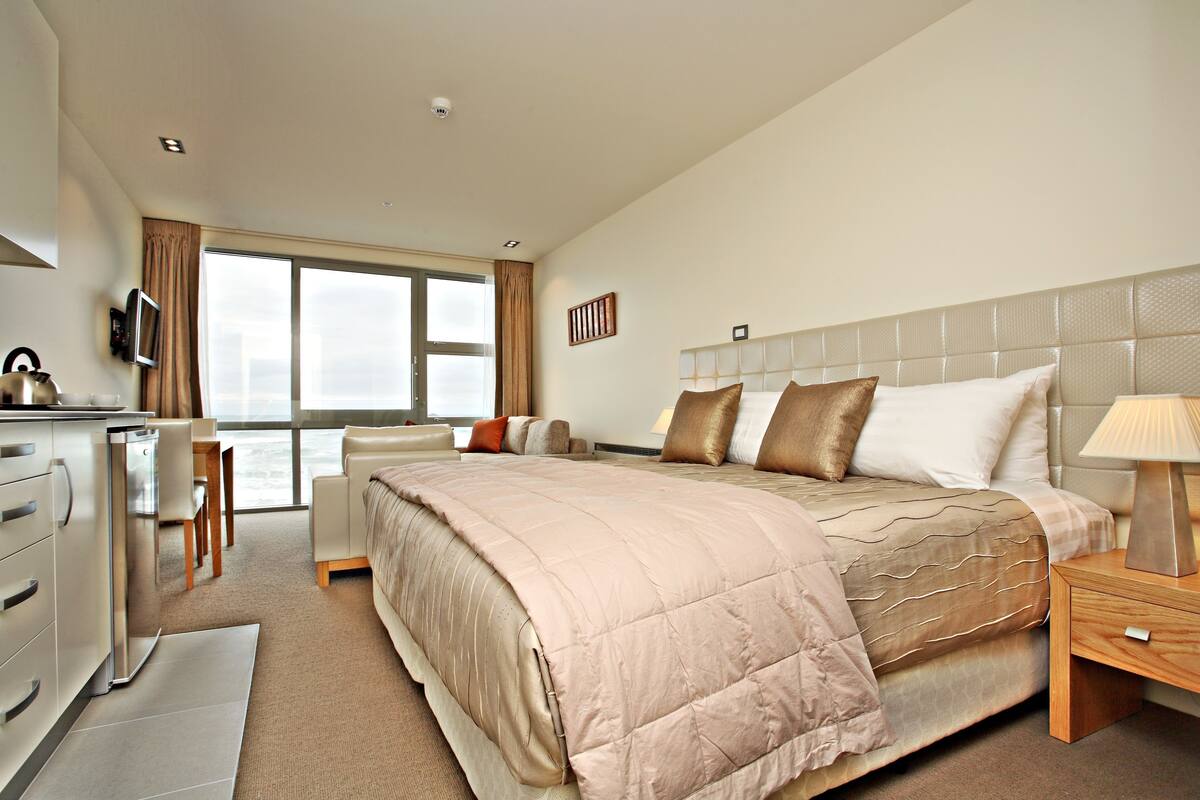 A modern hotel room with a large bed, a desk, and a chair.