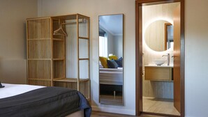 Ein Schlafzimmer mit einem Bett, einem Kleiderschrank, einem Spiegel und einem Badezimmer mit Waschbecken und Spiegel.