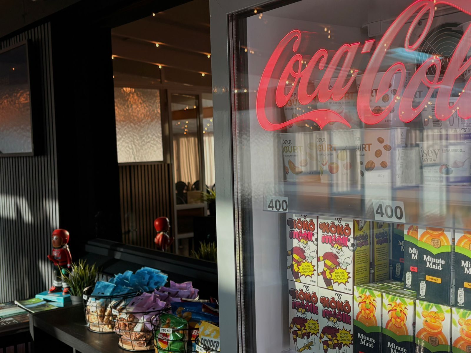 A store window with a Coca-Cola sign, shelves of packaged goods, and a price tag of 400.