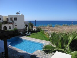 Una piscina al aire libre, sombrillas, sillones reclinables de piscina