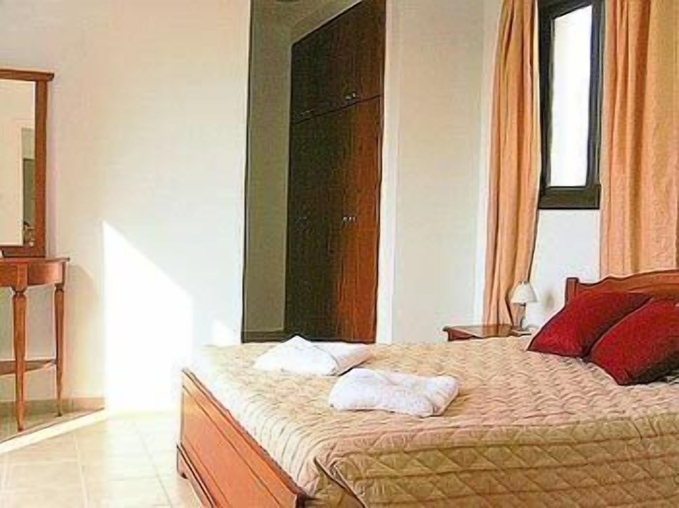 A bedroom with a bed, a wardrobe, a nightstand, and a mirror.