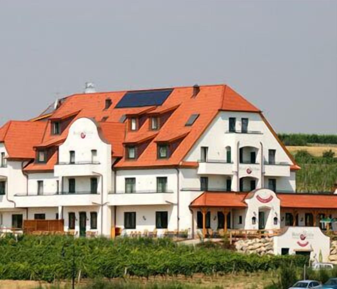A multi-story building with a red roof, white walls, and multiple balconies.