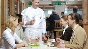 Uma área de refeições com um chef servindo comida para os hóspedes em uma mesa.