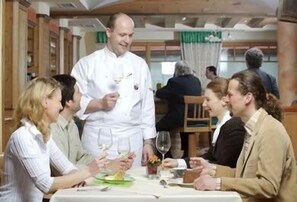 A dining area with a chef serving food to guests at a table. - Veltlin (Poysdorf)