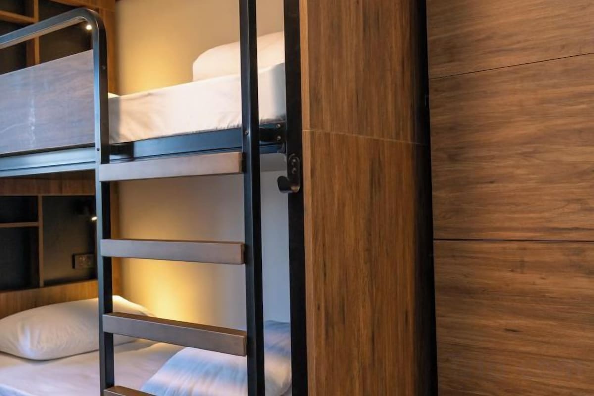 Een stapelbed met een ladder, houten wandpanelen en een plankenwand.