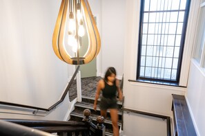A staircase with a modern light fixture and a window with bars. - Haka House Christchurch (Christchurch)