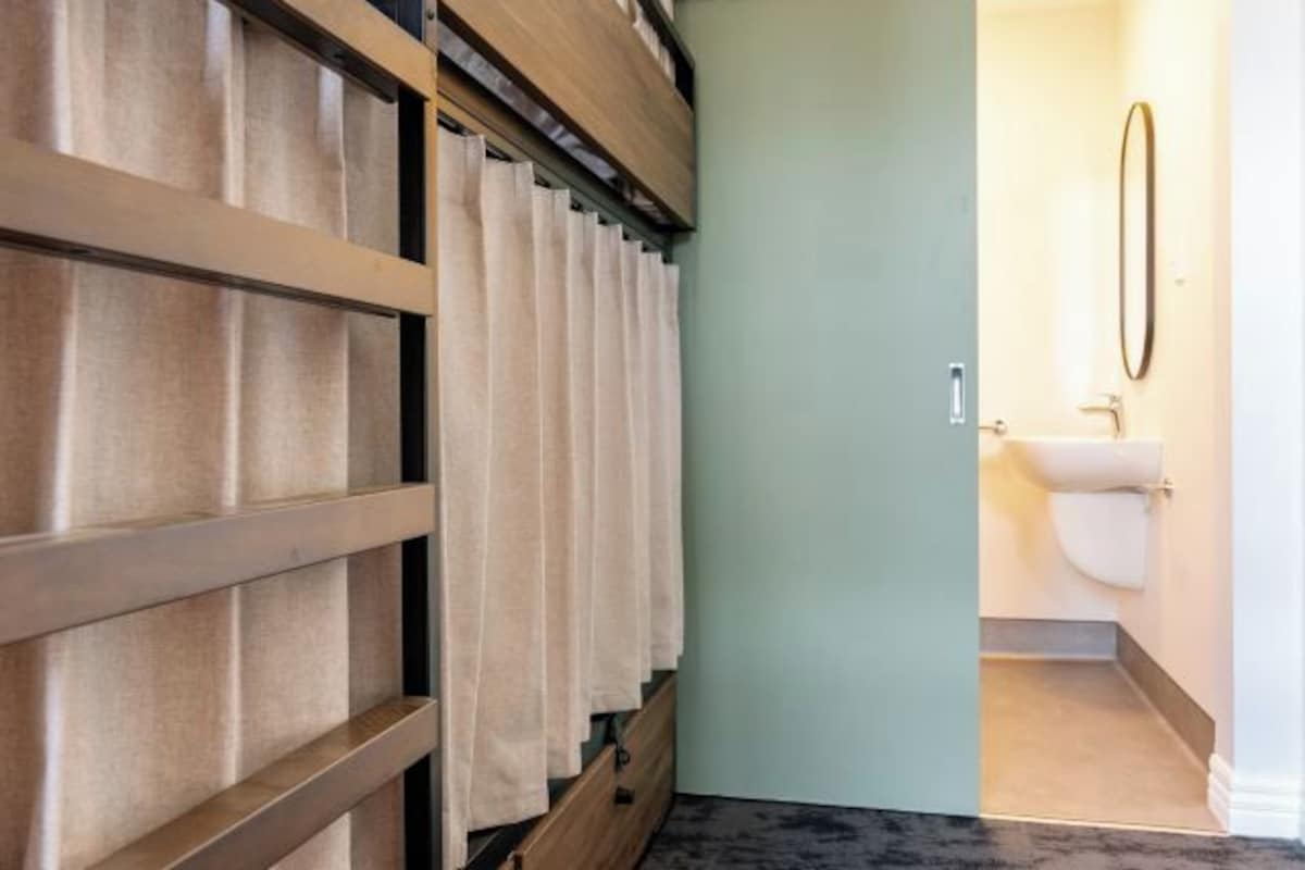 A room with a sliding wooden door, a white toilet, and a mirror on the wall.