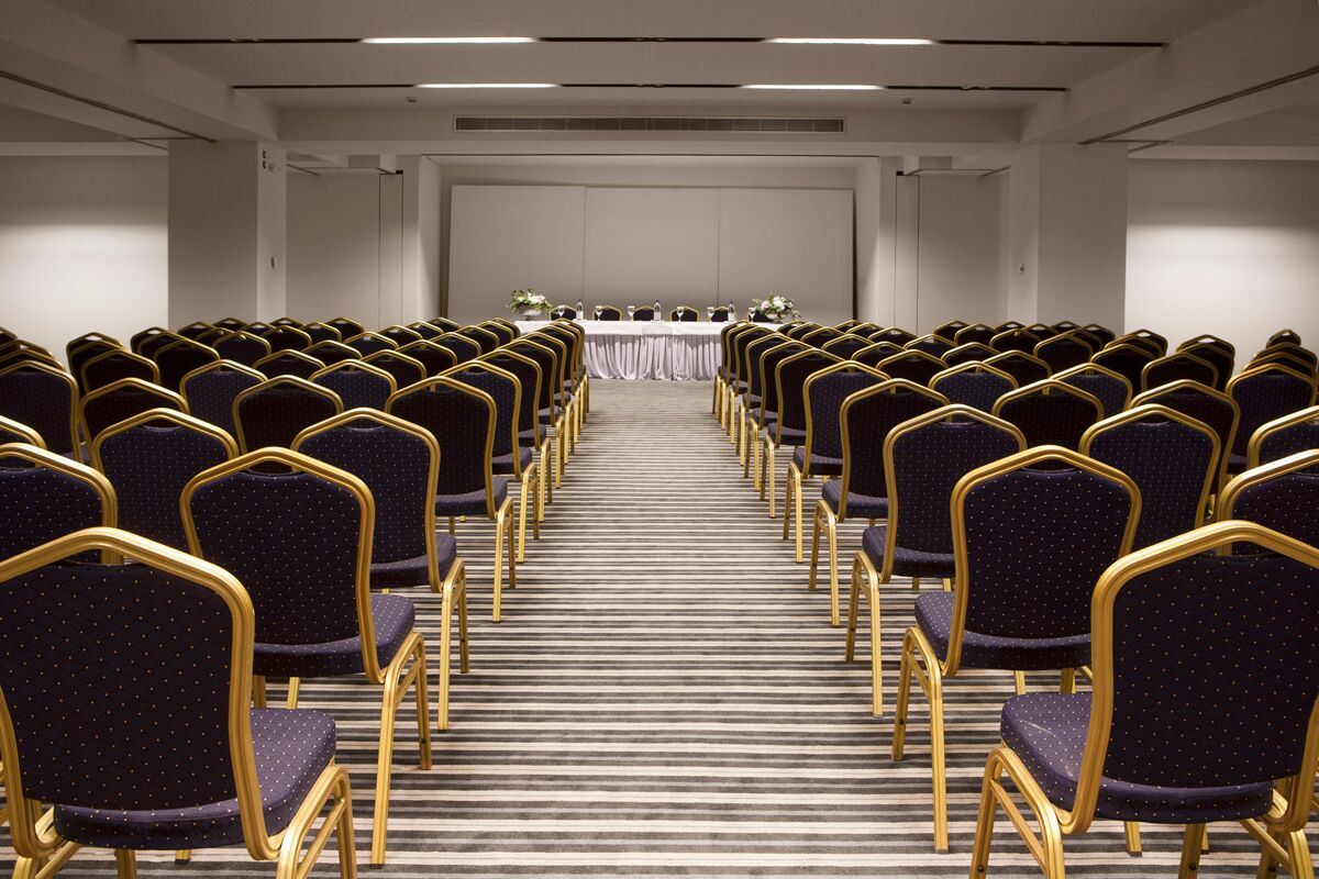 A conference room with rows of chairs and a long table at the front.