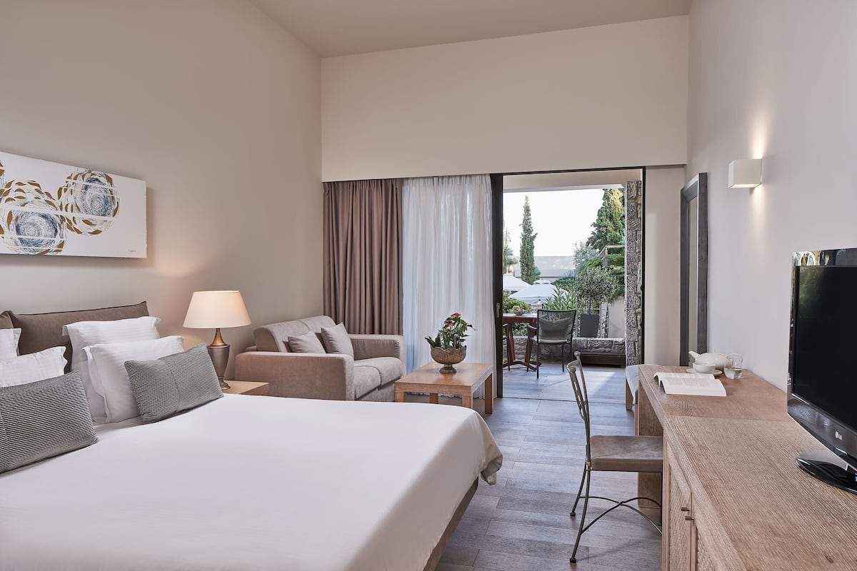Une chambre d’hôtel équipée d’un lit, d’un bureau, d’une télévision, d’une lampe et offrant une vue sur l’extérieur.