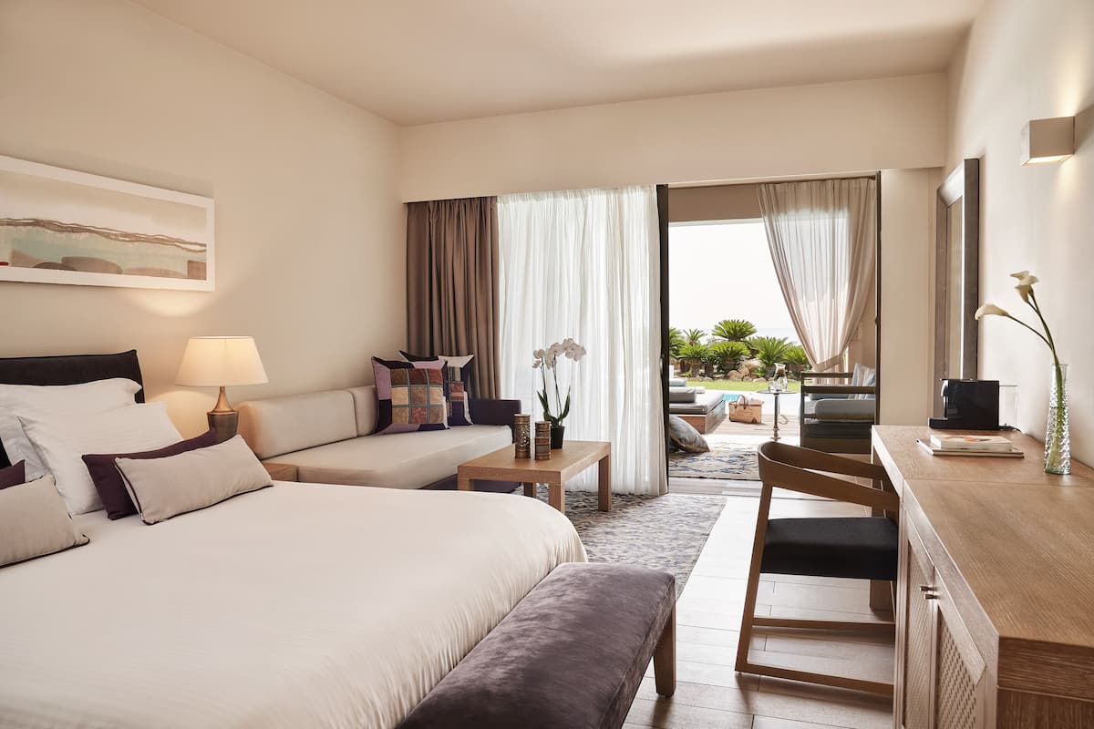 Une chambre d’hôtel équipée d’un lit, d’un canapé, d’un bureau et offrant une vue sur l’extérieur.