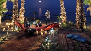 Una spiaggia con palme, una sedia a sdraio rossa e una persona che suona la chitarra.