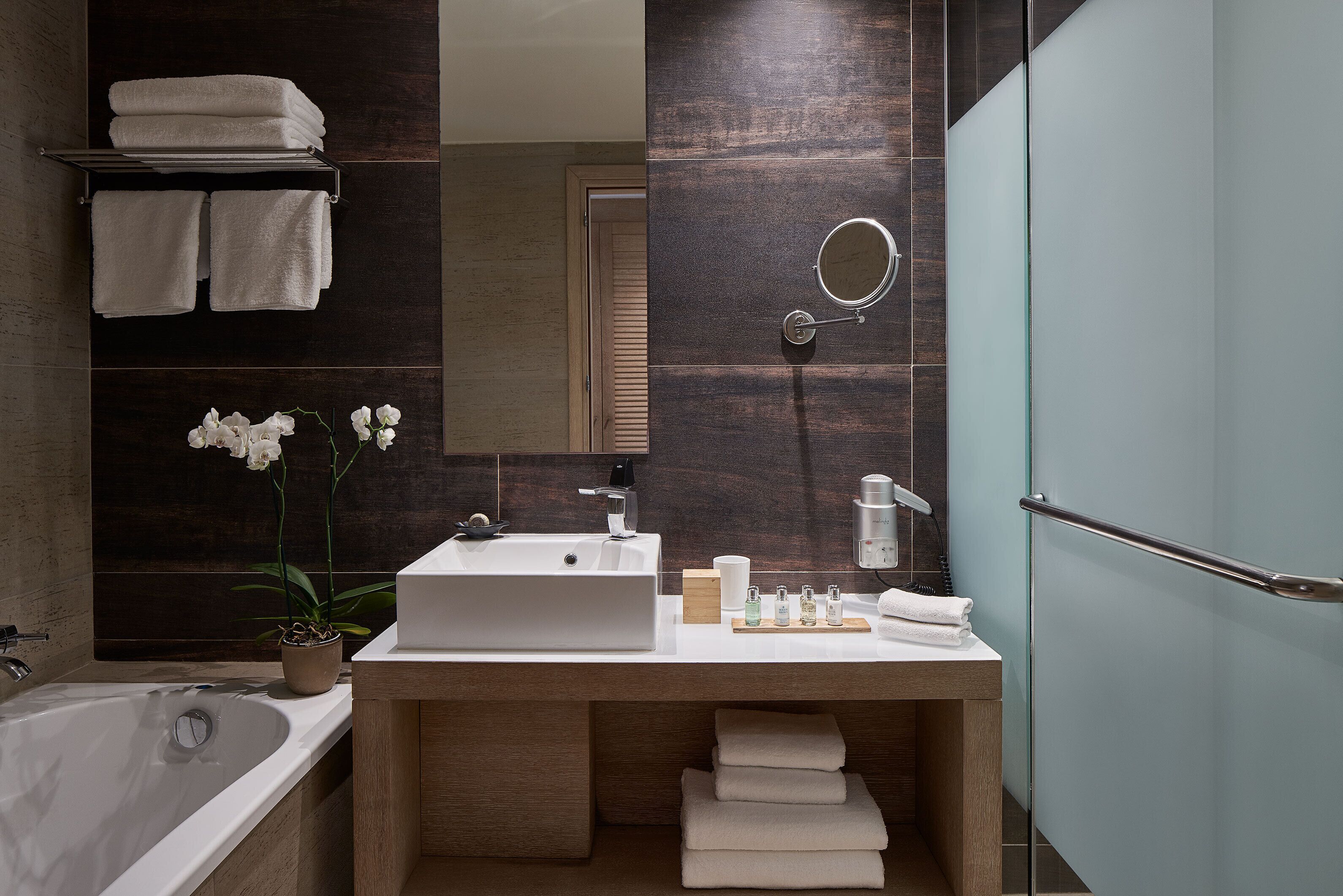 Un baño moderno con una bañera grande, un tocador de madera con un lavabo y un espejo.